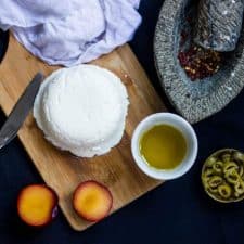 A picture of Homemade Cream Cheese on a wooden board along with Olive oil and Plum.