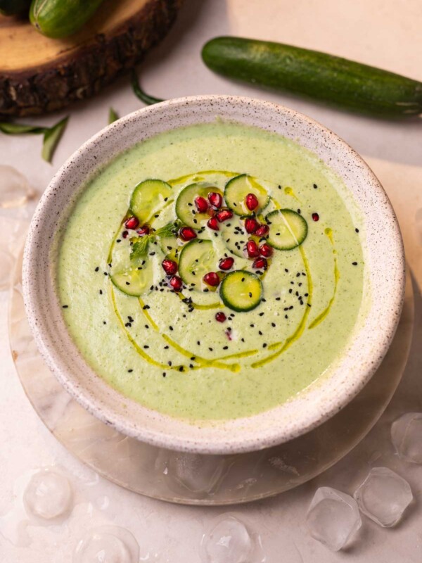 cold cucumber soup garnished with cucumber slices, pomegranate and nigella seeds ready to be served