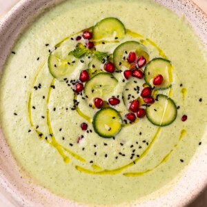 cold cucumber soup garnished with cucumber slices, pomegranate and nigella seeds ready to be served