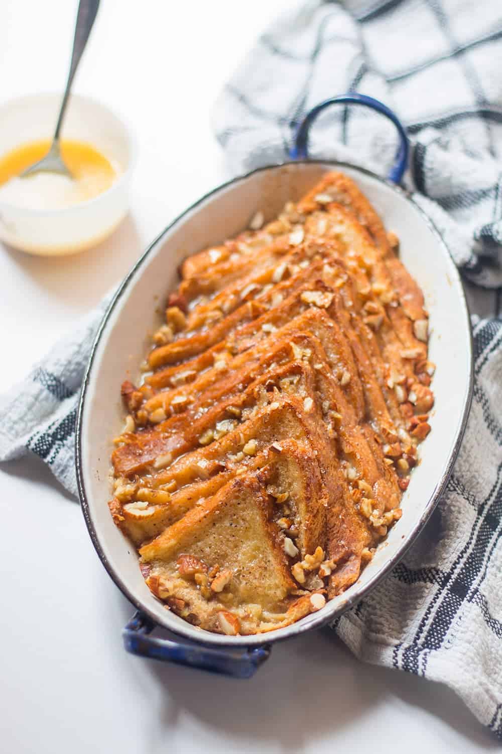 Cinnamon bread pudding served in an oval dish placed on a blue and white cloth