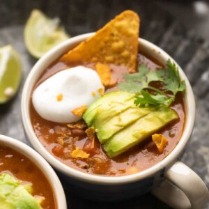 Picture of mexican soup served in a bowl topped with avocado, cilantro, sour cream and tortilla chips