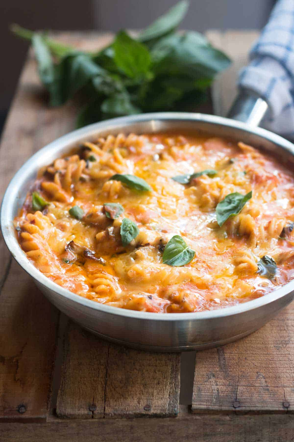 This all-in sunday veggie pasta is meant for those lazy Sunday evenings when all you want is a quick bowl of cheesy, comfort food. #pasta #vegetarian #onepot All-In Sunday Veggie Pasta layered with warm, melted cheese and garnished with fresh basil in a skillet.