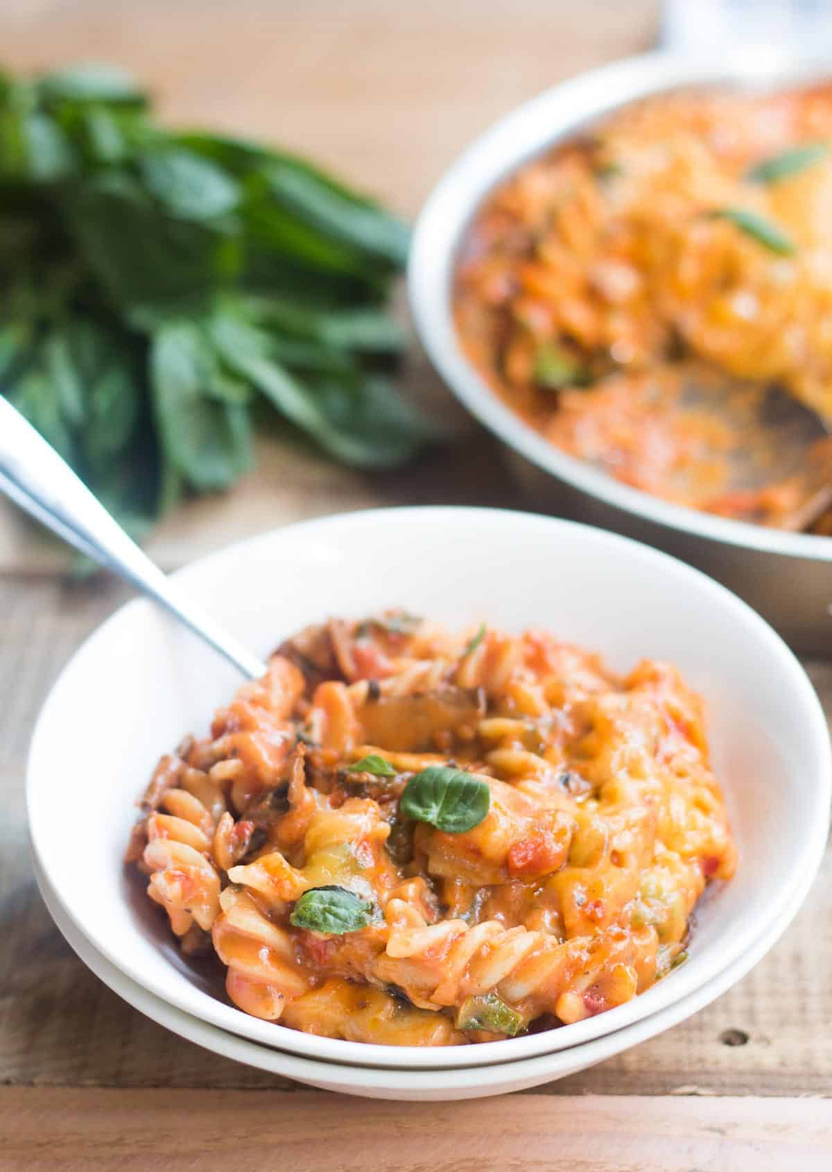 A comforting bowl of cheesy Sunday Veggie Pasta garnished with fresh basil and served in a white bowl.