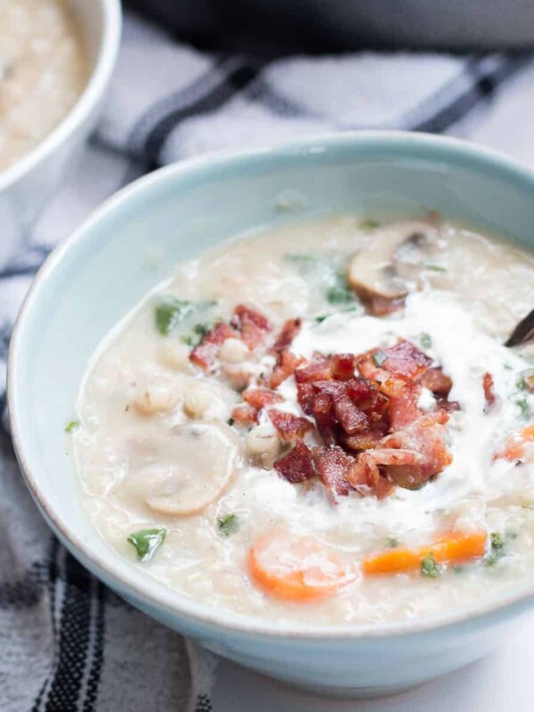 The soup garnished with bacon and cream and served in a white bowl.