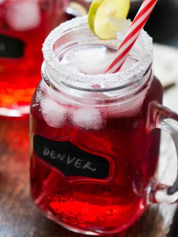 Cranberry Ginger Holiday Cocktail served in mason jars with sugar coated rims and a slice of lime. .