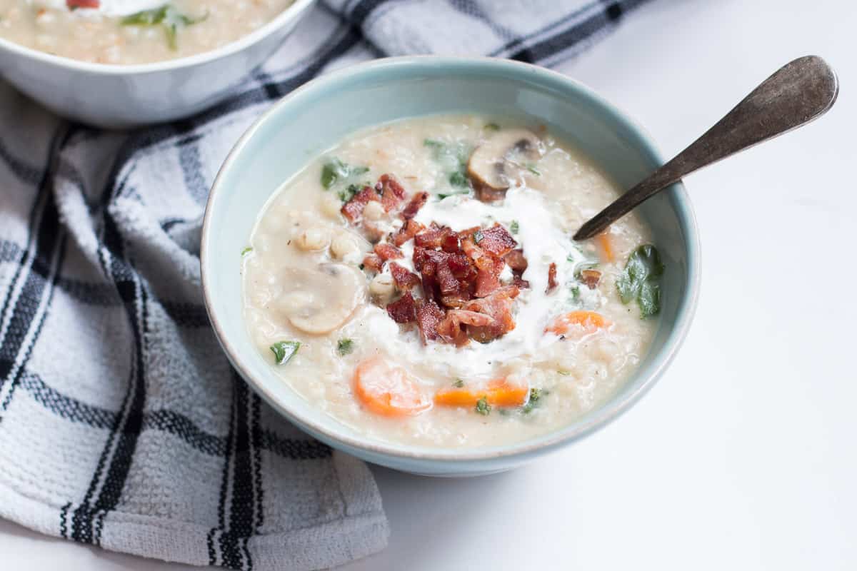 The soup garnished with bacon and cream and served in a white bowl.