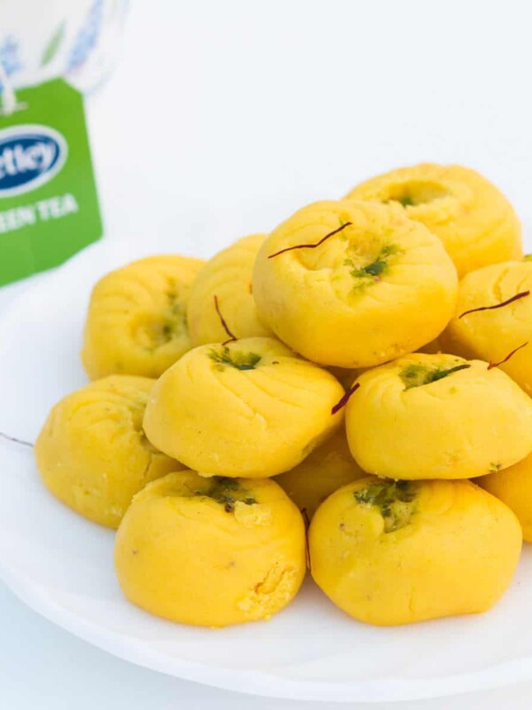 Easy Kesar Pedas served on a white plate with a side of Tetley green tea.