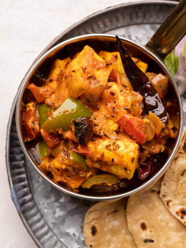 Achari Paneer served in a copper steel bowl with rotis on the side