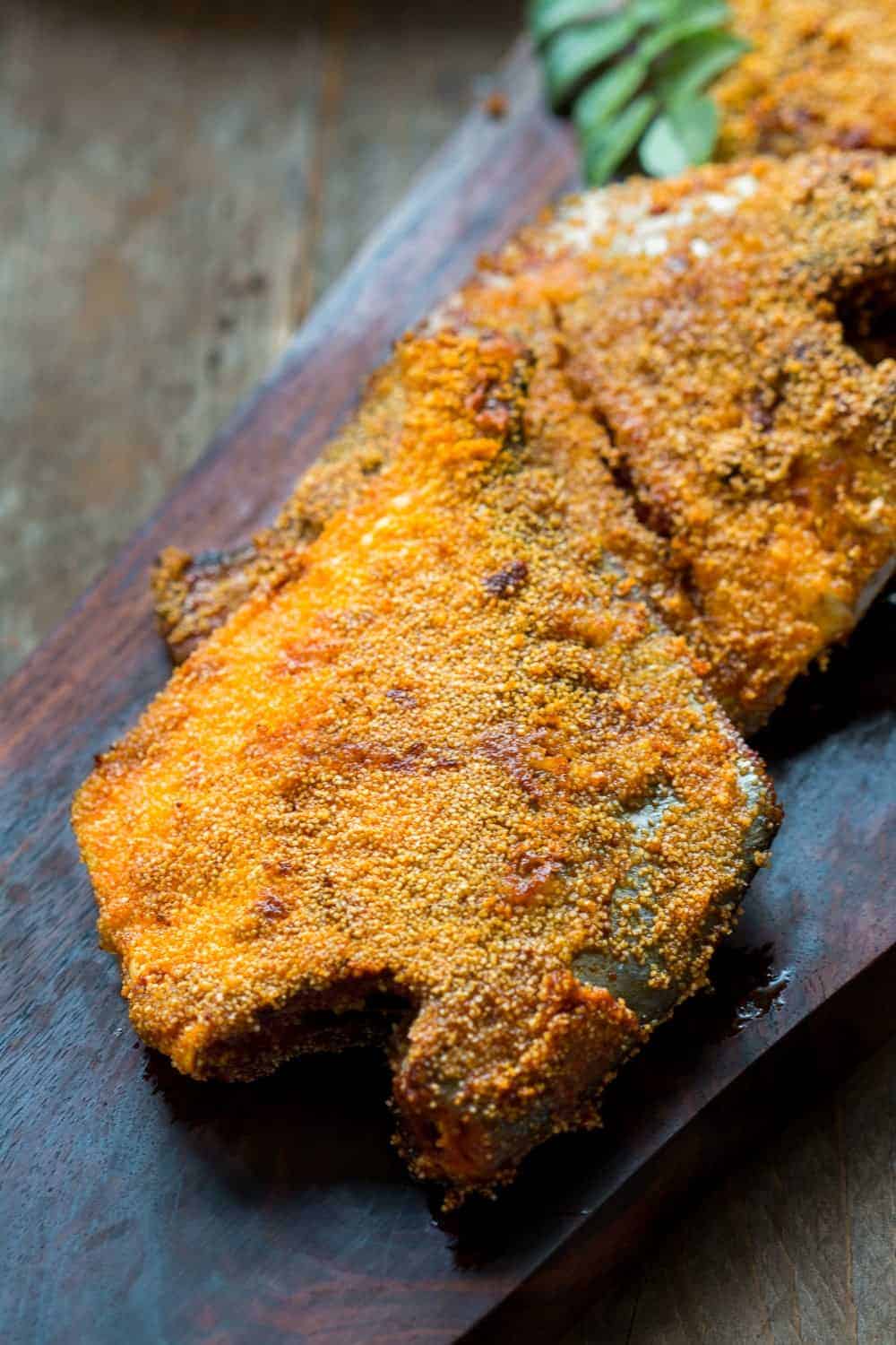 the fried fish coated with rava aka semolina served on a wooden board