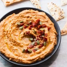 Sundried tomato hummus served in a black bowl with lavash.