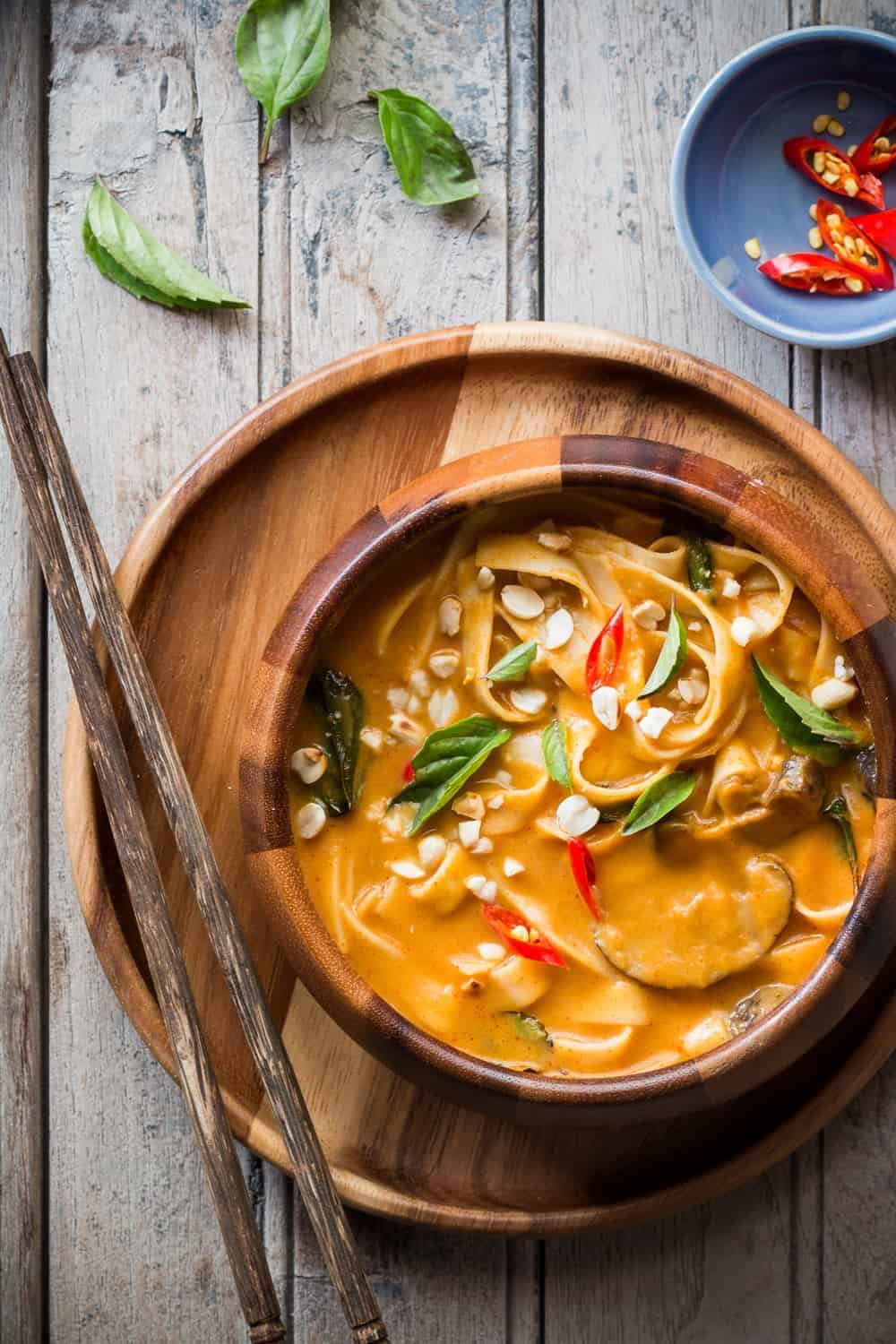 spicy thai curry pumpkin noodle soup served in a brown bowl