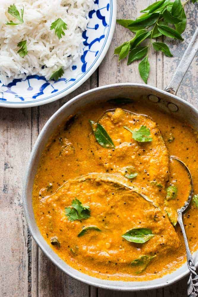 The kingfish curry garnished with curry leaves and served in a pan alongside rice.