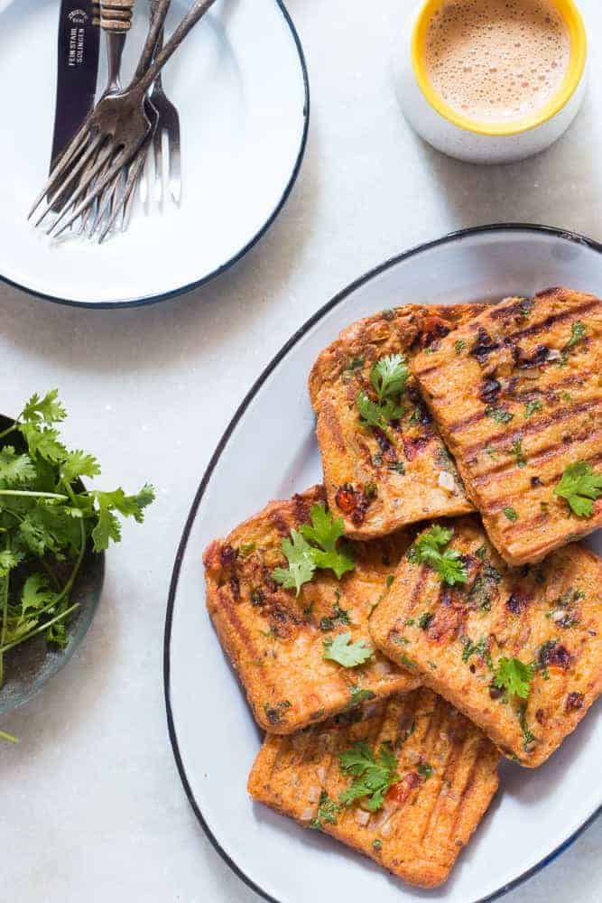 Indian masala egg french toast served in a white plate with hot cups of coffee on the side