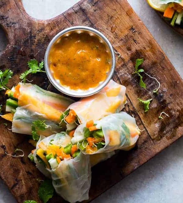 Mango Bell Pepper Rice Paper Rolls with Mango Cilantro Dipping Sauce served on a wooden board.