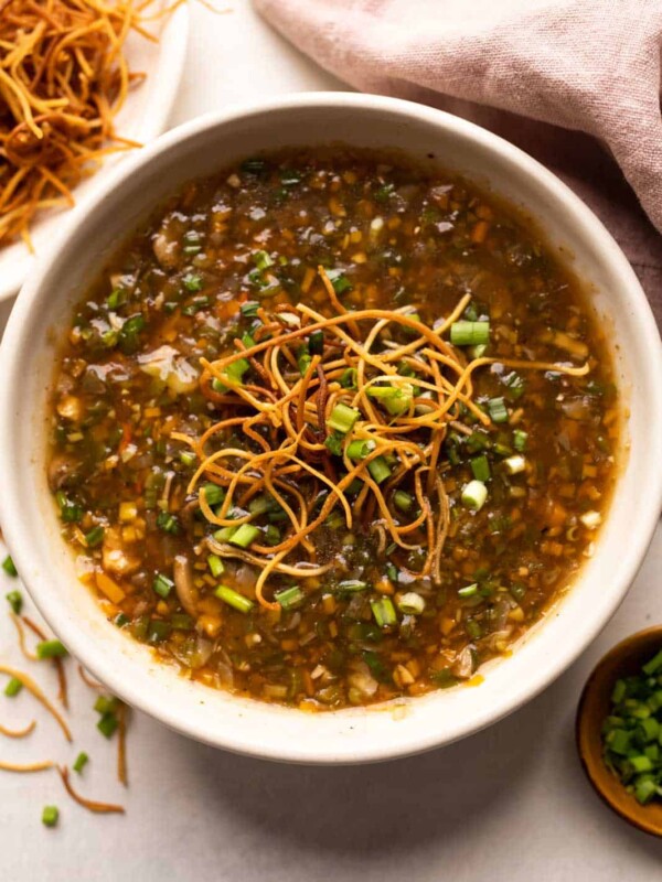 Chicken Manchow soup served in a white bowl topped with fried noodles and spring onions