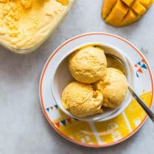 Three scoops of Homemade Mango Cheesecake Ice Cream served in a white bowl.