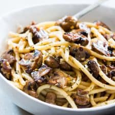 Mushroom spaghetti garnished with parmesan cheese and served in a white bowl.