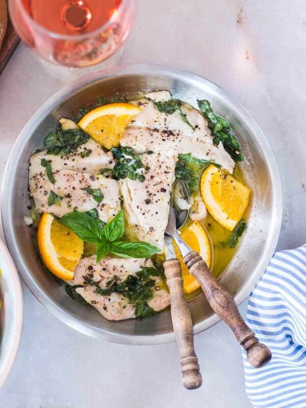 Bhetki Fish in Citrus Basil Butter Sauce served with a side of wine.