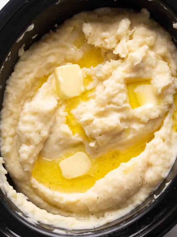 Mashed potatoes cooked and served in the slow cooker with blobs of butter on top