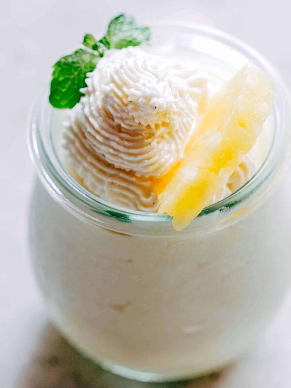 Eggless Pineapple Mousse garnished with mint and a slice of pineapple and served in a mini jar.
