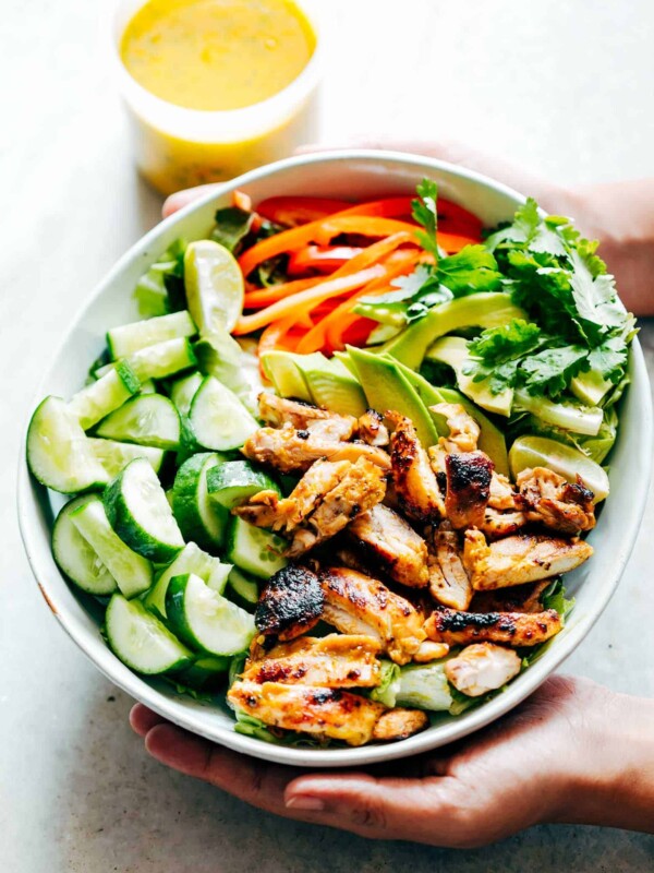A bowl full of ingredients of the salad with a side of the dressing.