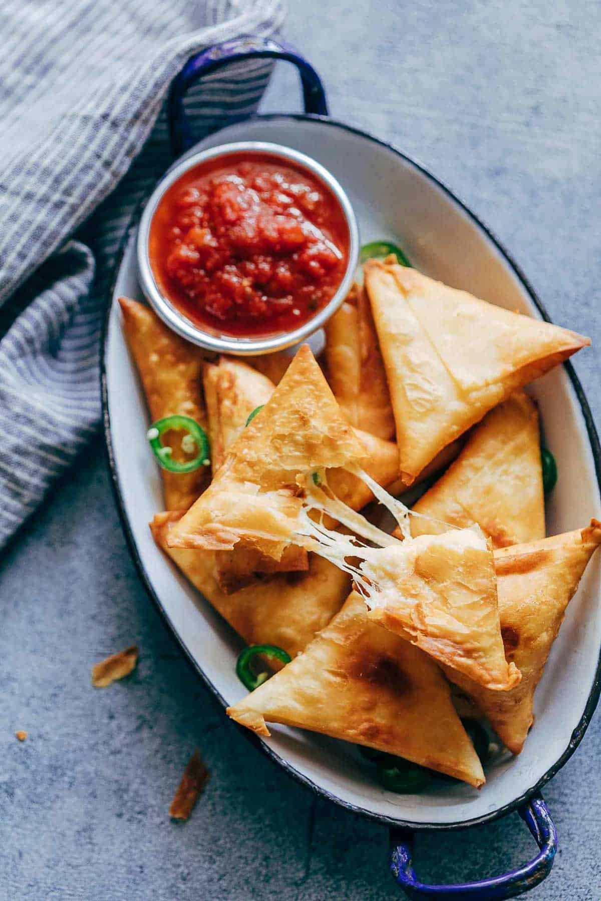 Super cheesy jalapeno three cheese samosa are sure to become a favourite because who can resist gooey stringy cheese stuffed in crispy samosa wrappers! These vegetarian samosas have a filling of mozzarella, cream cheese, smoked cheddar and jalapenos and folding them is really easy too.ย