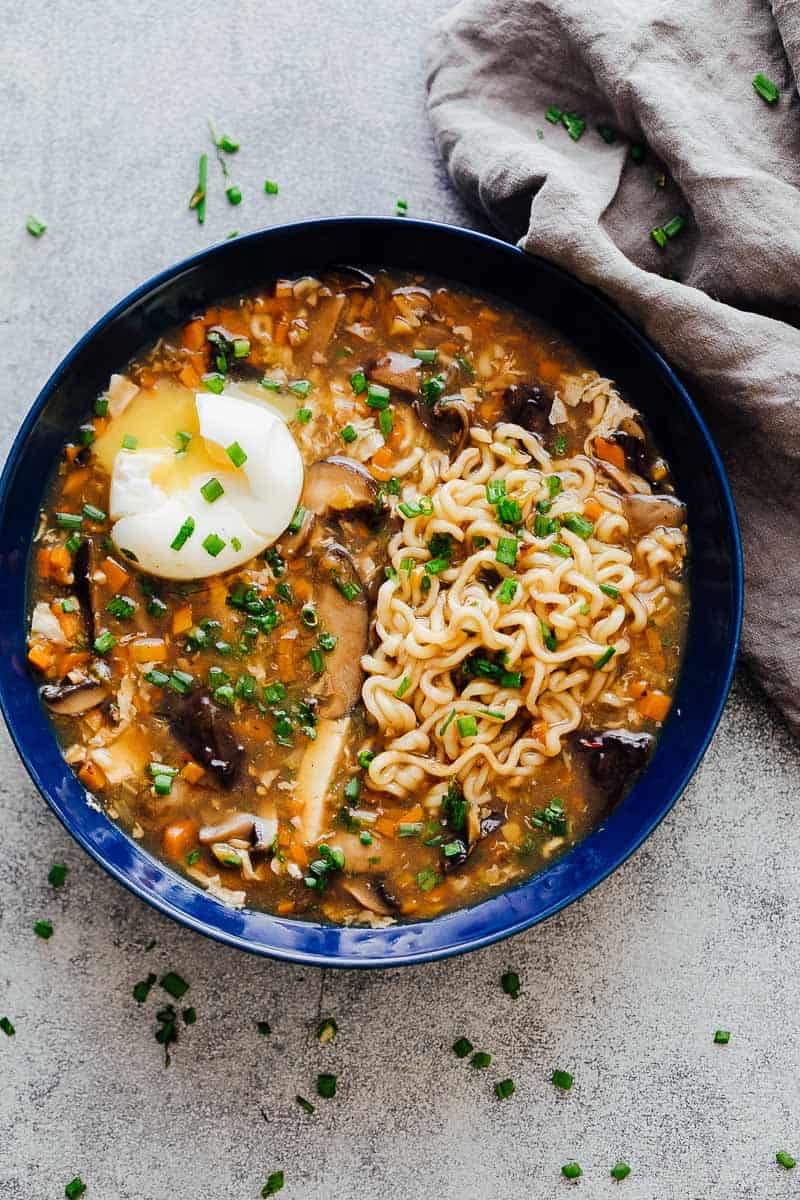 A bowl of chinese hot and sour soup with ramen served with a soft boiled egg and green onions ready to eat!