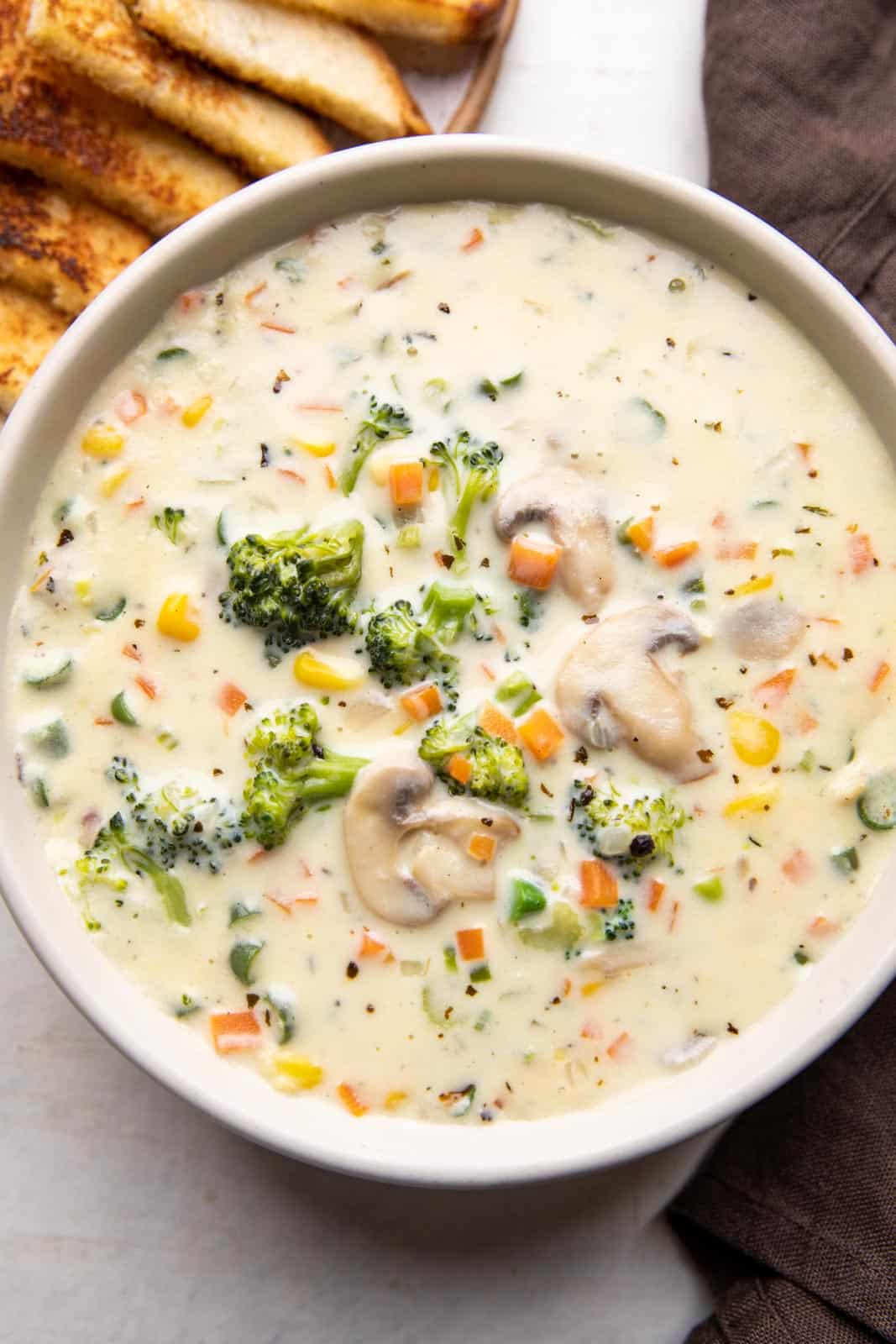 Creamy vegetable soup served in a bowl with bread on the side