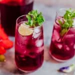 Hibiscus iced tea finished off with mint, lemon and served in glasses.
