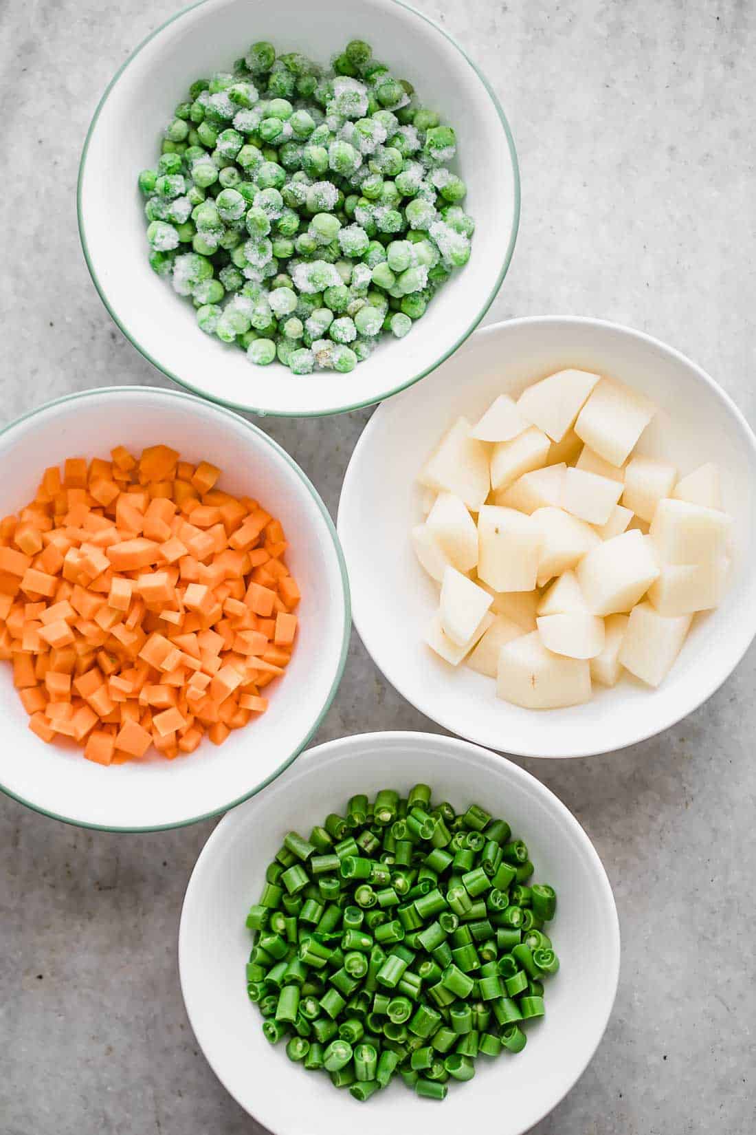 This pressure cooker VEGETABLE PILAF (rice pulao/ pilav) recipe is fragrant, fluffy and perfect every single time! Make this healthy and easy mixed vegetable rice (like biryani) in under 30 minutes. Seasoning includes whole spices and cooked with lots of vegetables, this is the perfect Indian side dish. #sides #recipe #dinner #fast #onepot #vegetarian Mise en place for pressure cooker veg pulao. Pcture of frozen green peas, carrots, beans and potatoes n bowls all ready to go into the recipe