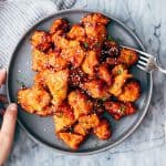 Korean Popcorn Chicken on a plate with a hand coming up to take a bite with a fork