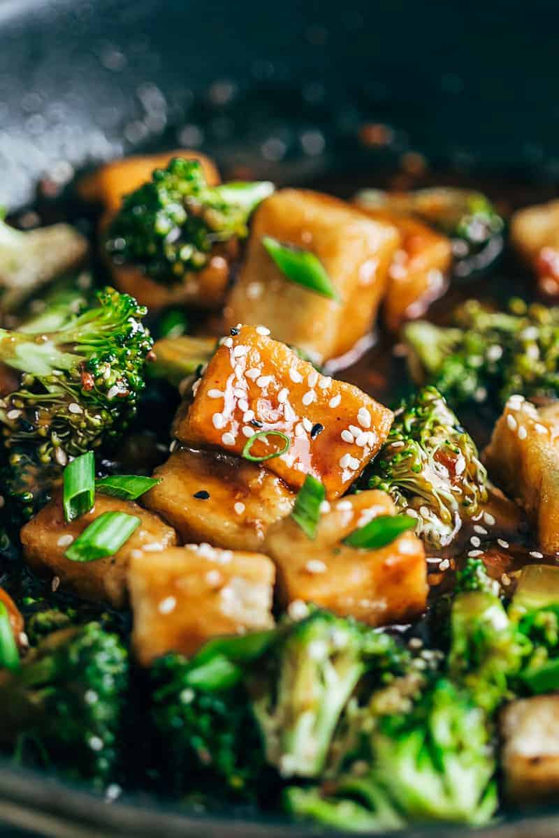 Closeup of crispy tofu broccoli stir fry garnished with toasted sesame seeds and spring onions