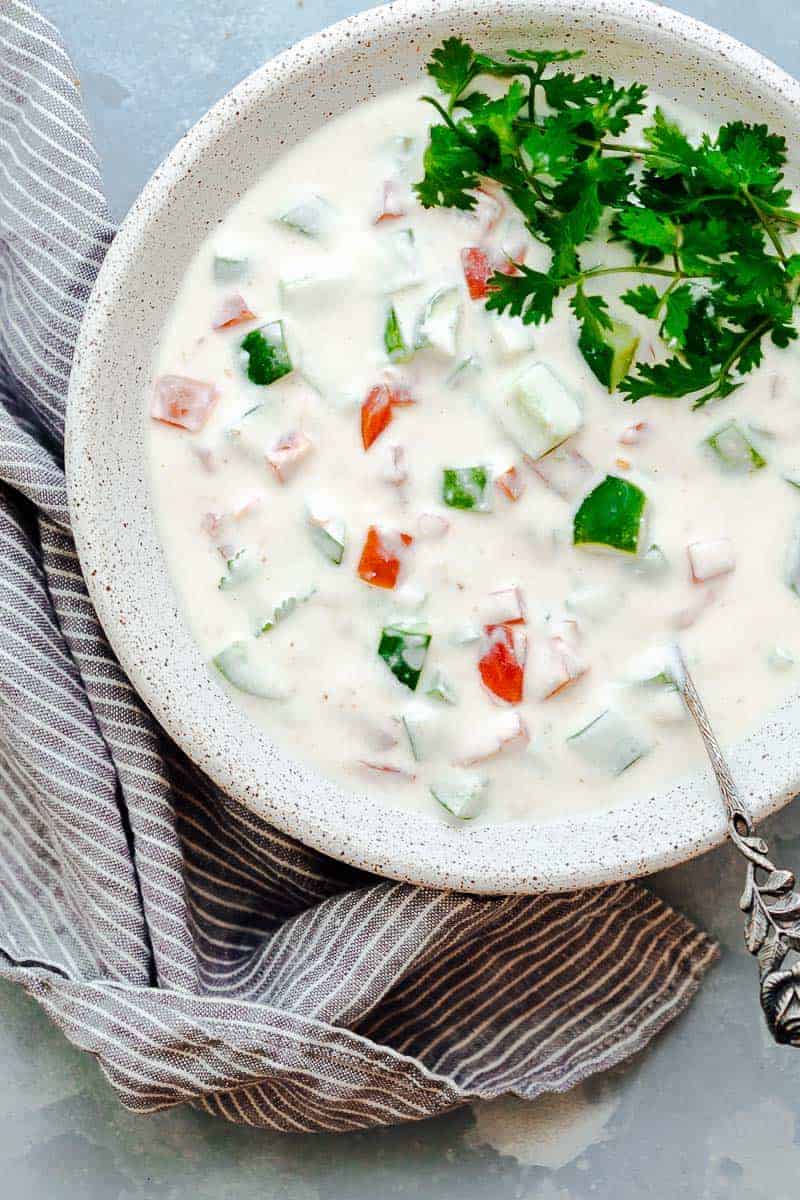 Indian raita served in a white bowl topped with coriander or cilantro