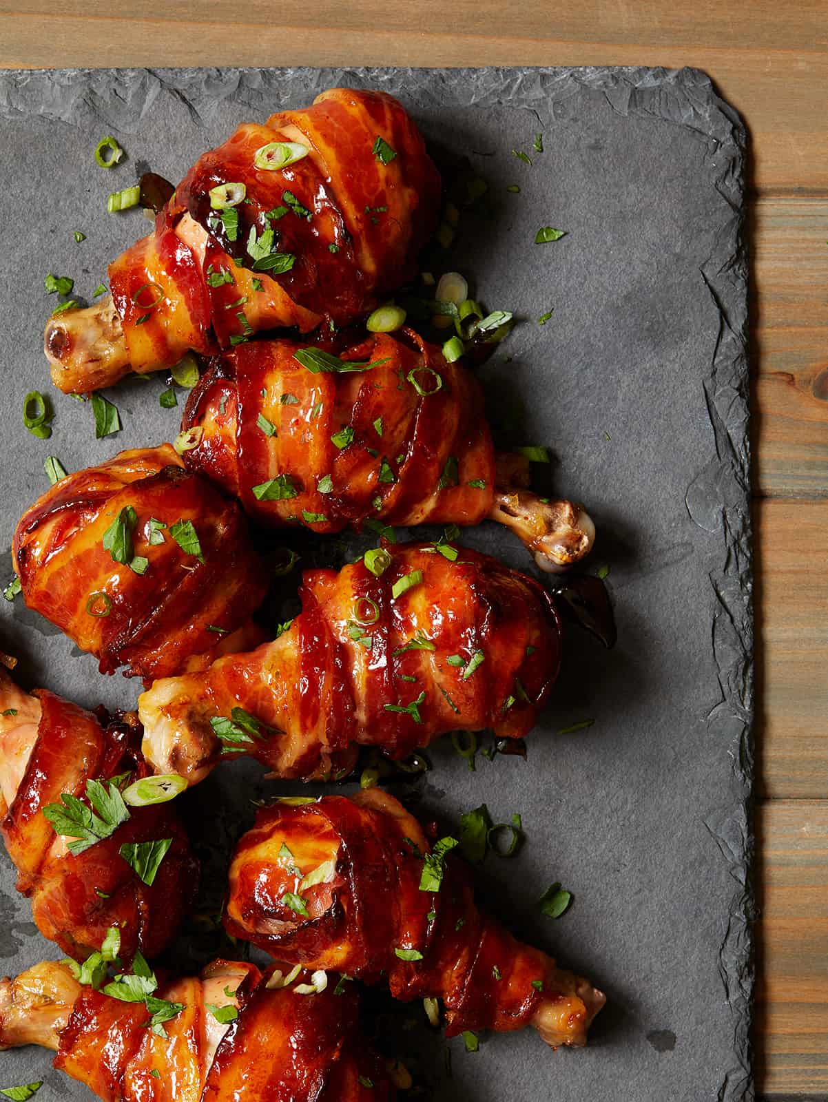 Maple Bacon chicken drumsticks laid out on a slate serving board