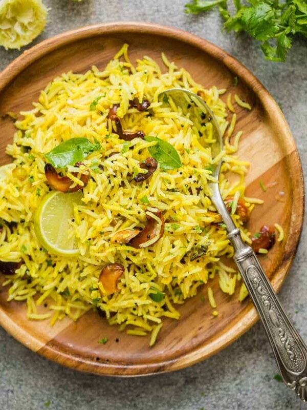 Flavorful lemon rice served on a wooden plate with a spoon.