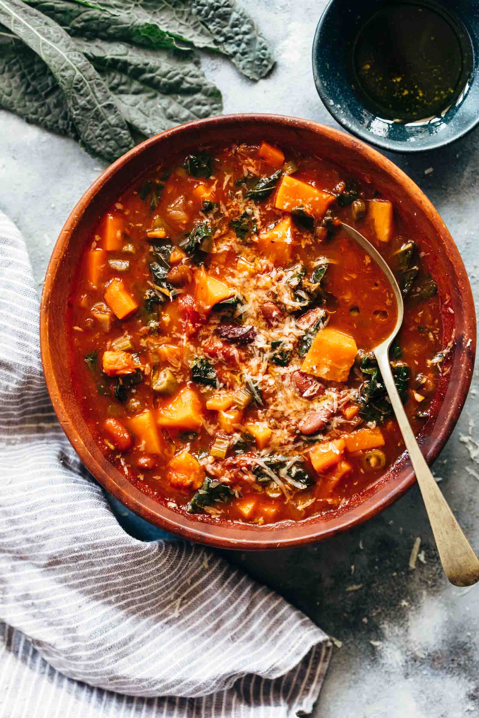 Winter Vegetarian Minestrone Soup served in a bowl topped with parmesan and olive oil