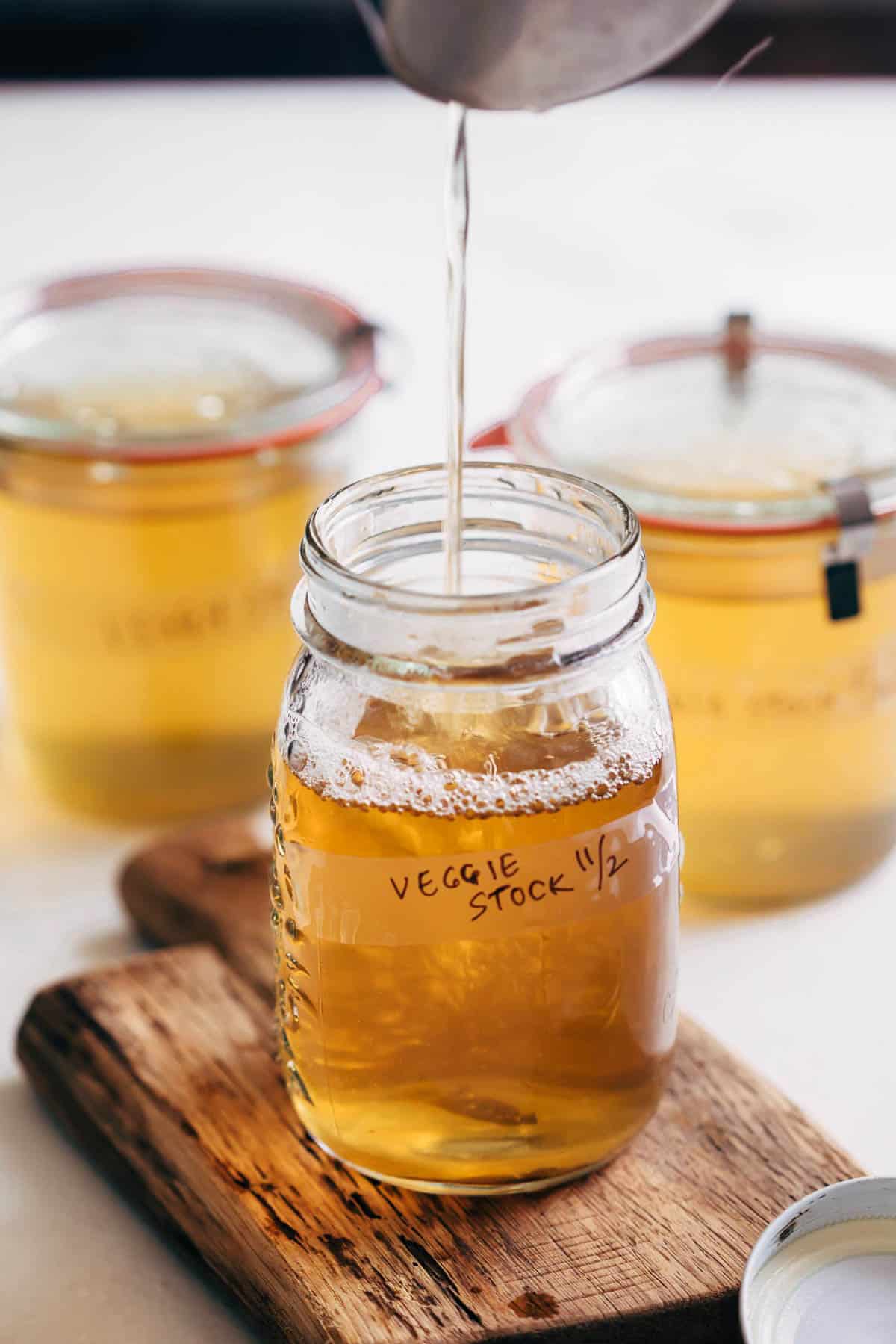 Homemade vegetable stock strained into a canning jar