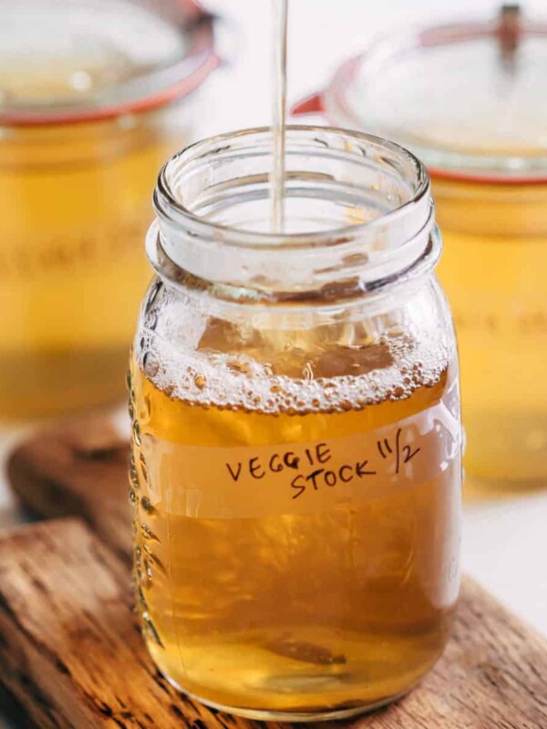 Homemade vegetable stock strained into a canning jar