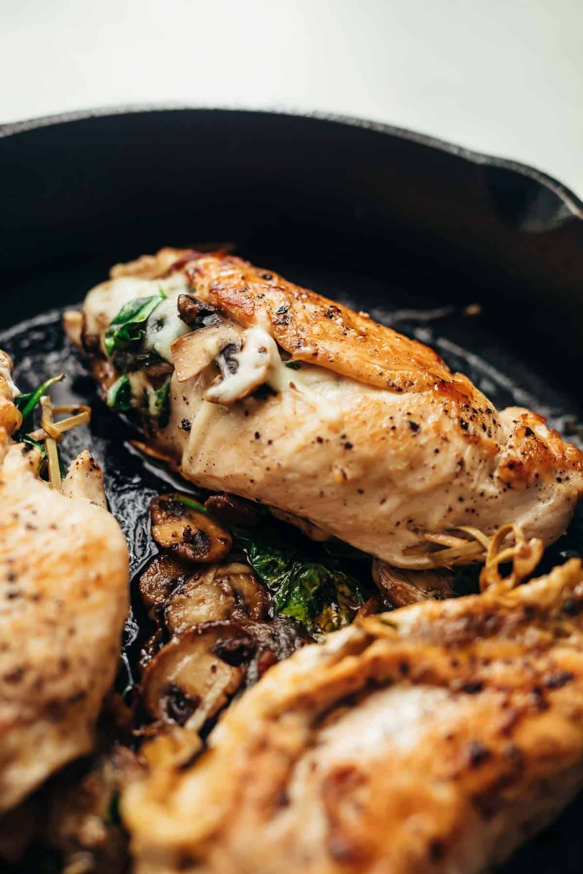 Spinach Mushroom stuffed Chicken Breast cooked in a cast iron pan.