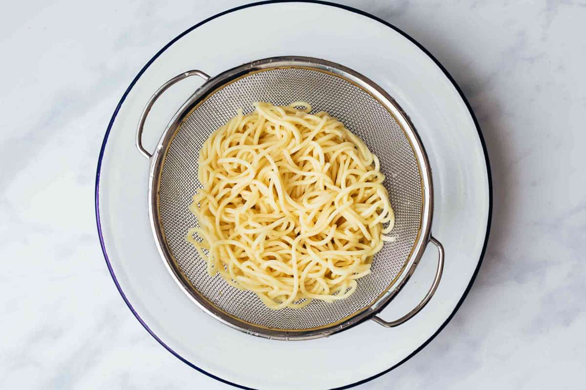 Boiled noodles drained in a colander for crispy fried noodles
