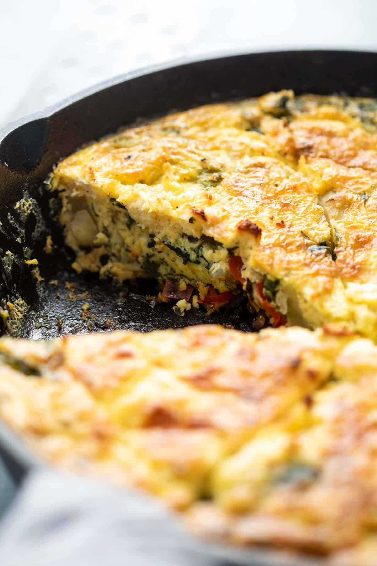Closeup of sliced spinach potato veggie frittata in a cast iron skillet