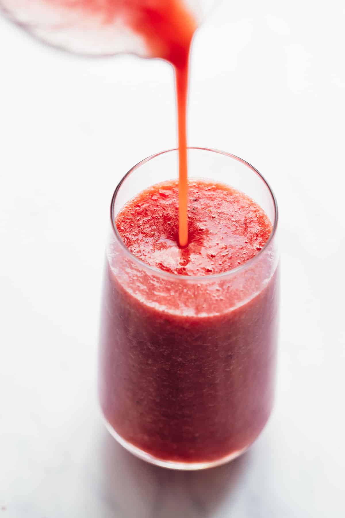 Pouring blended watermelon lime smoothie into a glass
