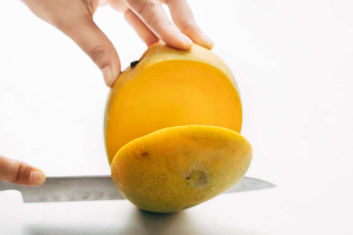 Cheeks of a mango being cut out.
