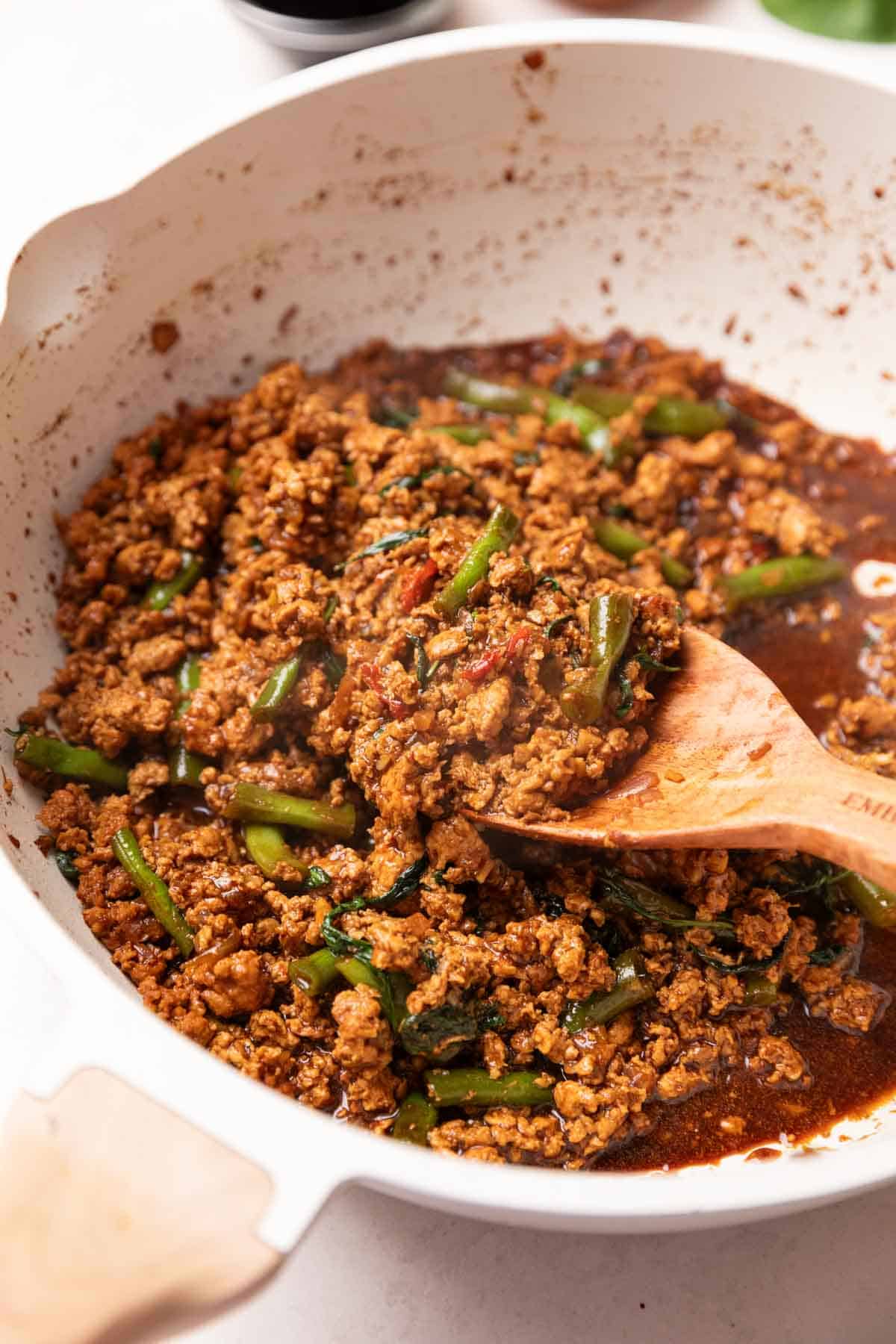 thai basil chicken with beans being made in a frying pan