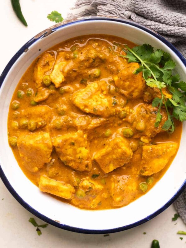 shot of matar paneer gravy in a white bowl with coriander sprinkled on top