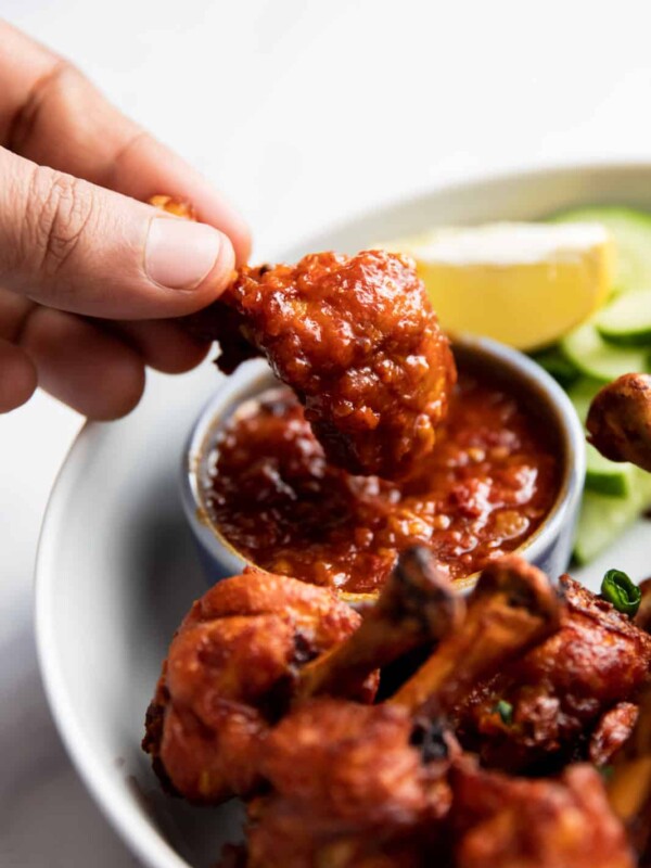 Dipping chicken lollipop in schezwan sauce