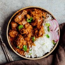 Slow cooker lamb curry served in a plate with rice and sliced onions