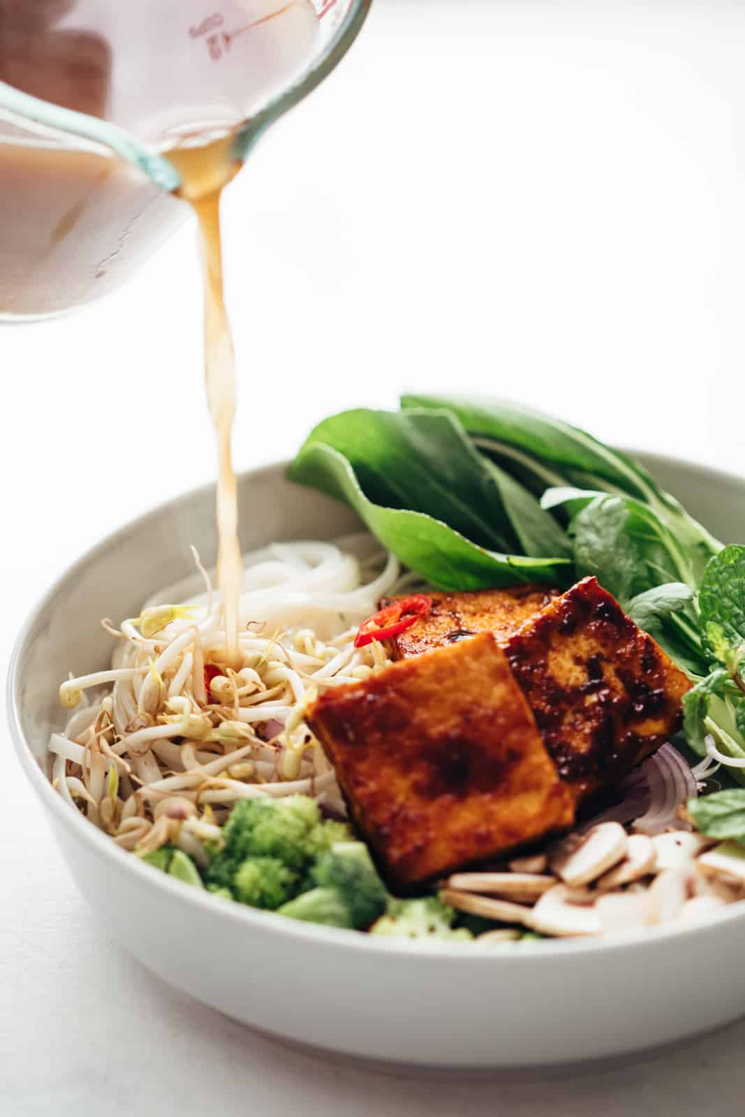 Pouring stock over vegetarian pho soup