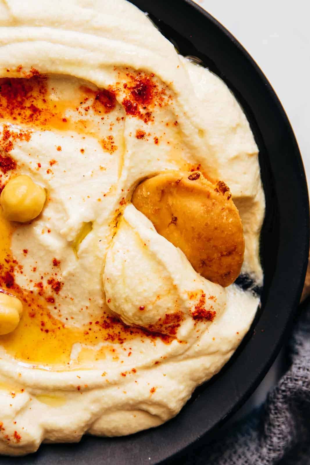 Closeup of pita scooping up hummus to show smooth texture