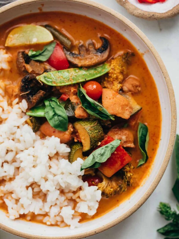 Closeup of Instant pot Thai chicken curry served in a bowl with rice, thai red chillies and lemon wedges